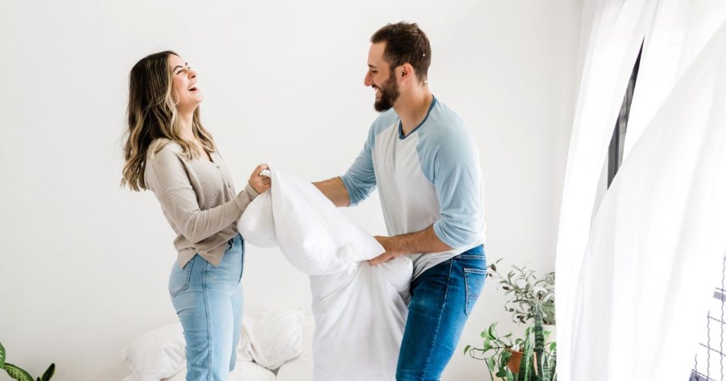 Couple playing with organic latex pillow. 