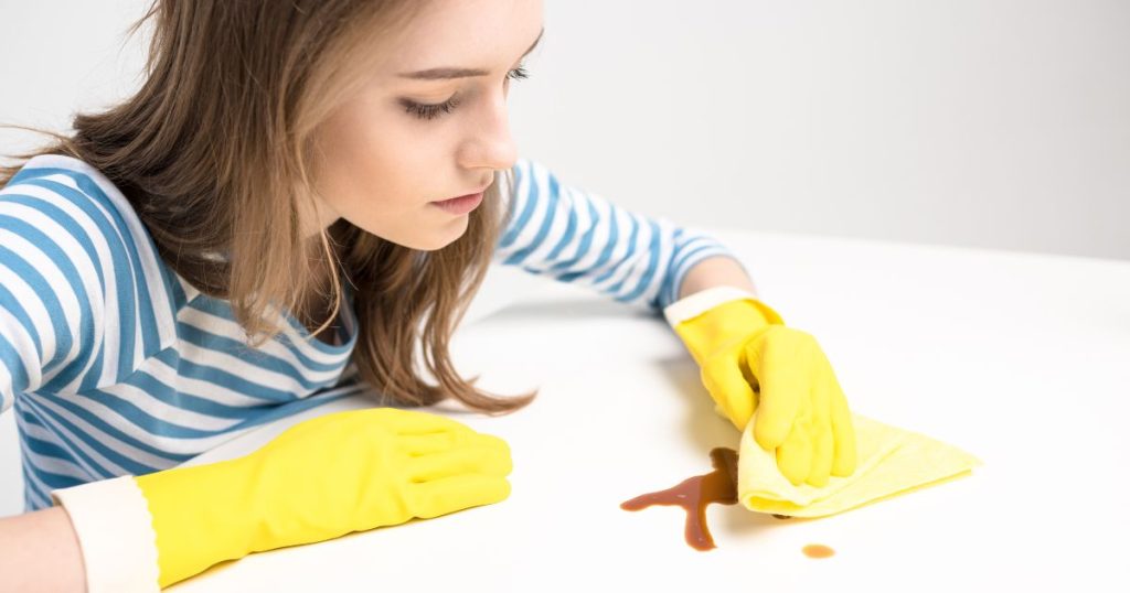 Woman caring for a latex mattress by using a damp cloth to gently clean a stain.
