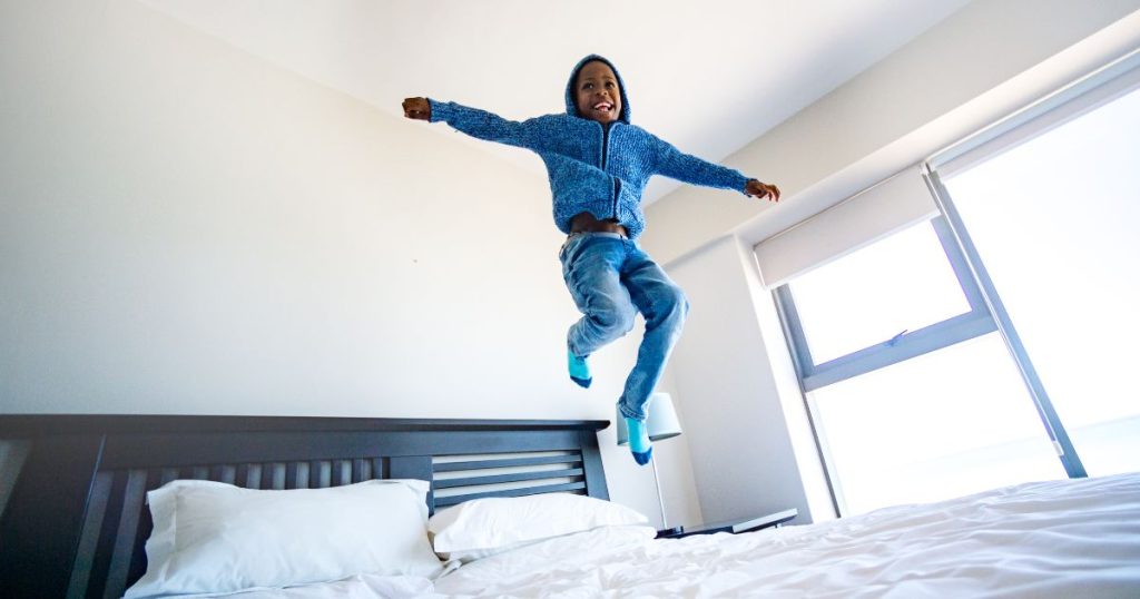 Little boy jumping on an organic latex mattress; illustrating how durable organic latex mattresses are. 