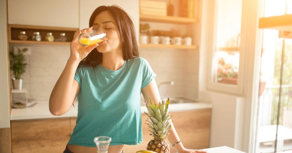 Woman drinking fruit juice in her kitchen after a good night's rest. 