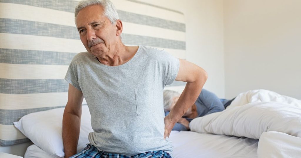 Man experiencing back ache from worn out pocket spring mattress.