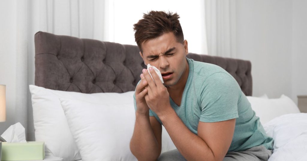 Man experiencing allergies caused by goose down duvet inner.