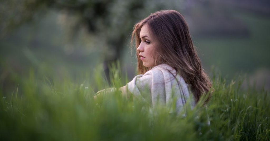 Woman sitting in a field of tall grass.