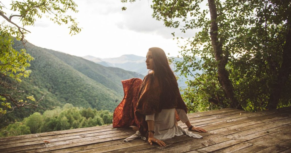 Woman sitting on a deck overlooking a valley and mountains