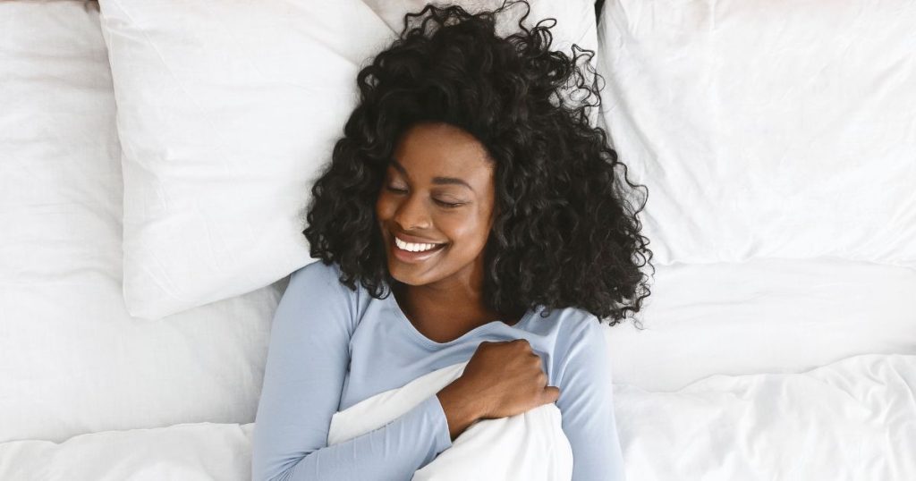 Woman smiling while she rests on an organic latex mattress