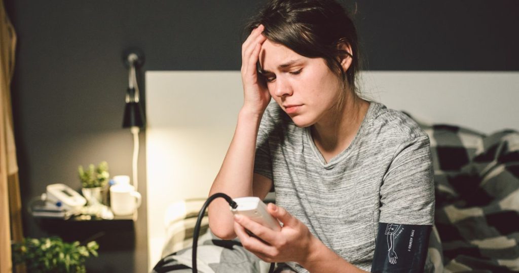 Woman measuring her blood pressure in bed after a sleepless night