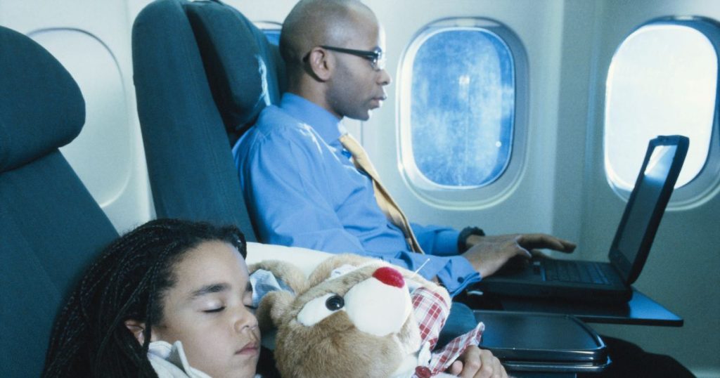 Man working on his laptop while travelling overnight on an airplane