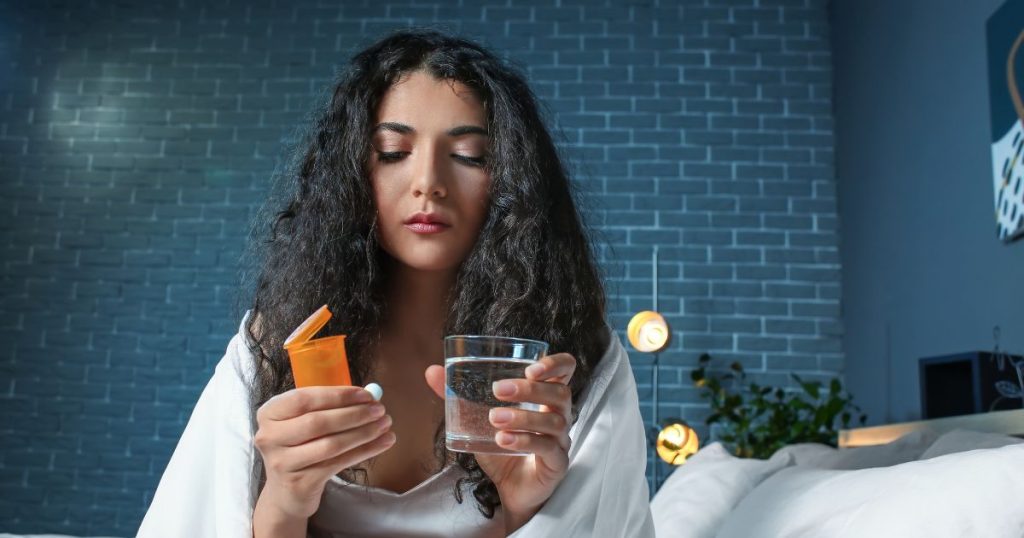 Woman holding a bottle of medication   to try help her sleep.