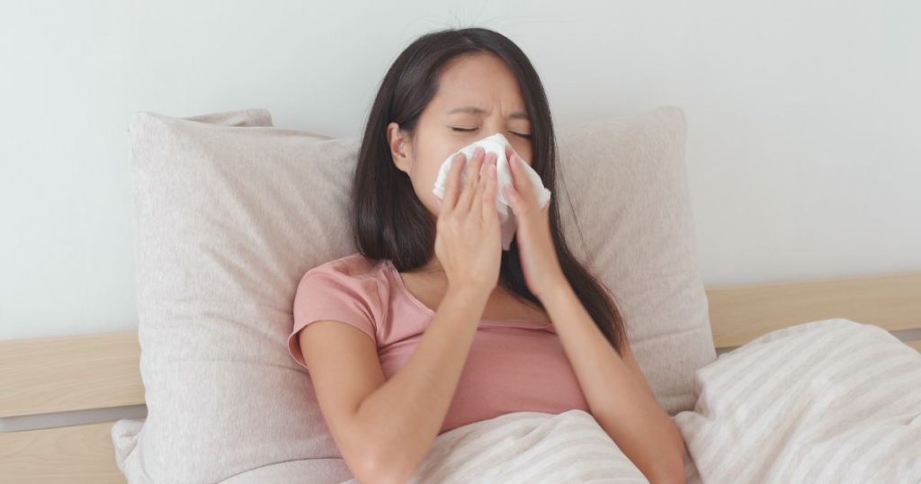 Woman sneezing in bed due to allergens in her mattress