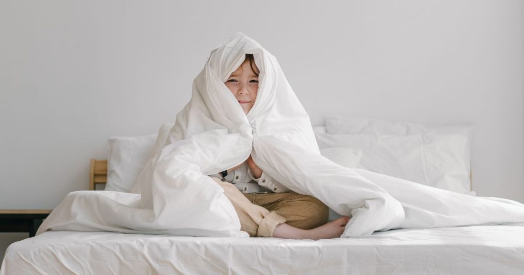 Happy young boy wrapped up in a pure wool duvet